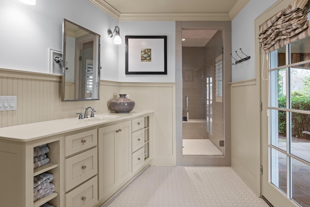 bathroom with a stall shower, wainscoting, and crown molding