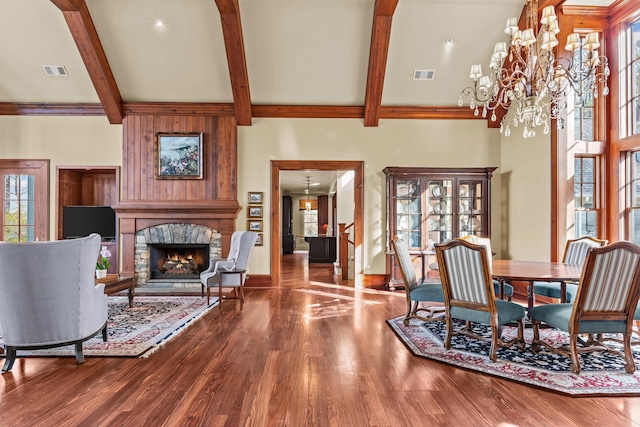 living area with beam ceiling, visible vents, a stone fireplace, and wood finished floors