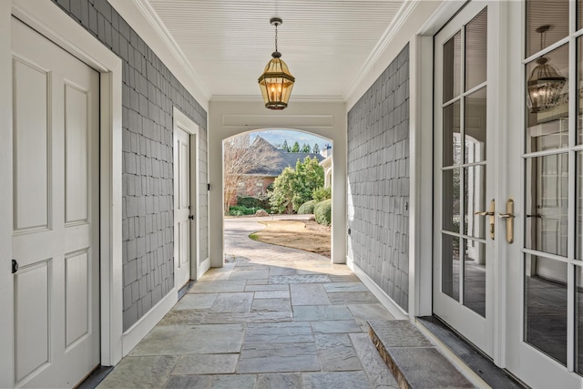 exterior space with stone tile floors, french doors, crown molding, and baseboards