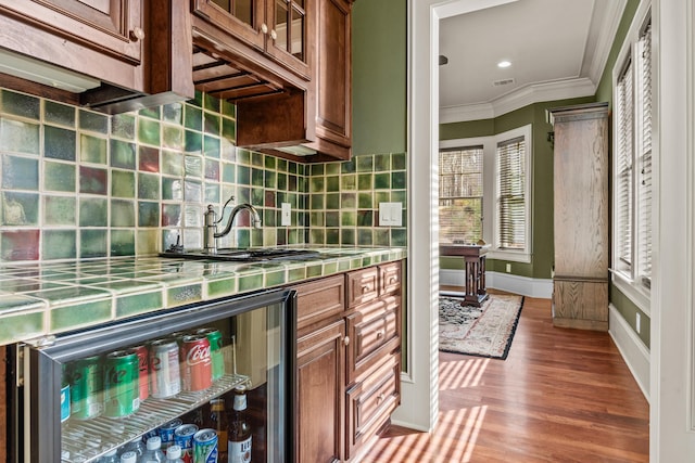 kitchen featuring visible vents, ornamental molding, backsplash, wood finished floors, and tile counters