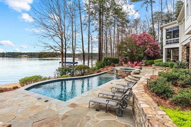 view of swimming pool featuring a pool with connected hot tub, a patio, and a water view