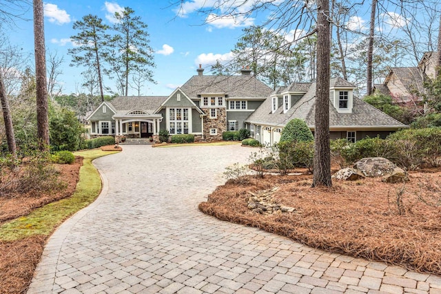 shingle-style home featuring decorative driveway, a garage, and covered porch