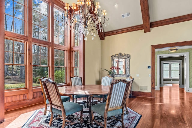 dining room with a notable chandelier, visible vents, baseboards, and wood finished floors