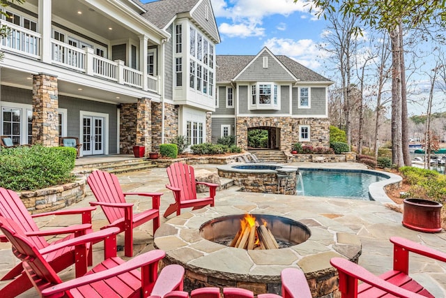 view of pool featuring an in ground hot tub, french doors, an outdoor fire pit, and a patio