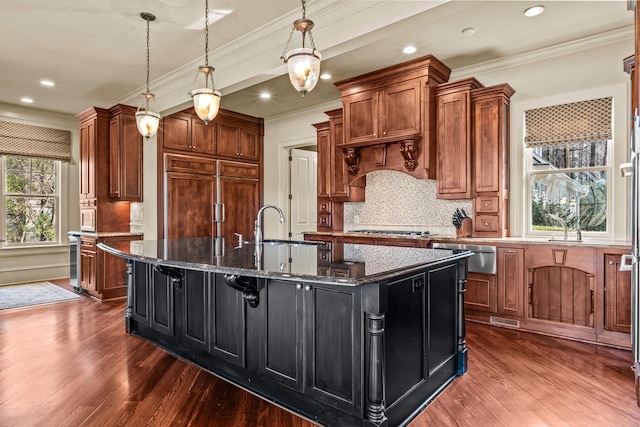 kitchen featuring a spacious island, ornamental molding, paneled built in refrigerator, a warming drawer, and a sink