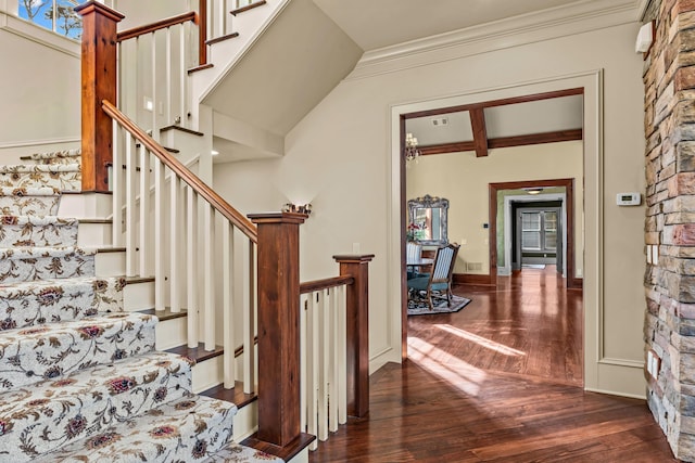 stairs with beamed ceiling, baseboards, wood finished floors, and crown molding