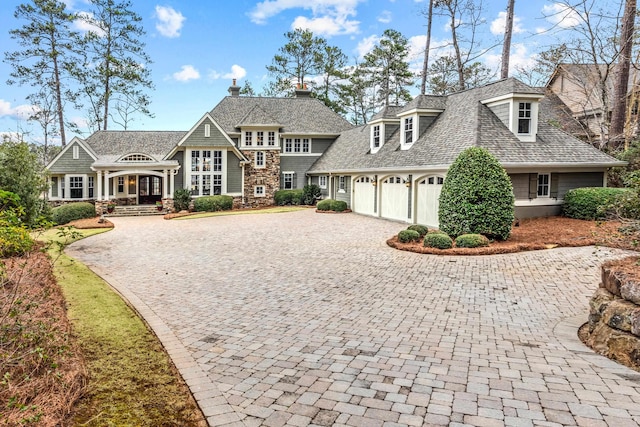 view of front of home with decorative driveway, a garage, roof with shingles, and a porch