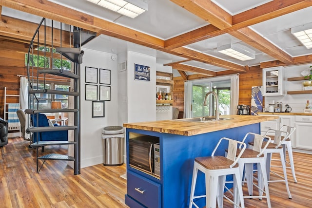 kitchen featuring wood counters, sink, white cabinetry, a kitchen breakfast bar, and a kitchen island with sink