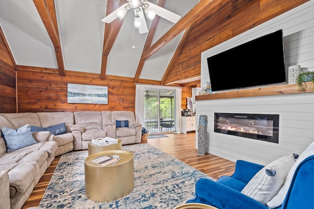 living room featuring ceiling fan, wooden walls, light hardwood / wood-style floors, and beam ceiling