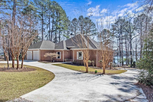 view of front of property with brick siding, driveway, a chimney, and a front lawn