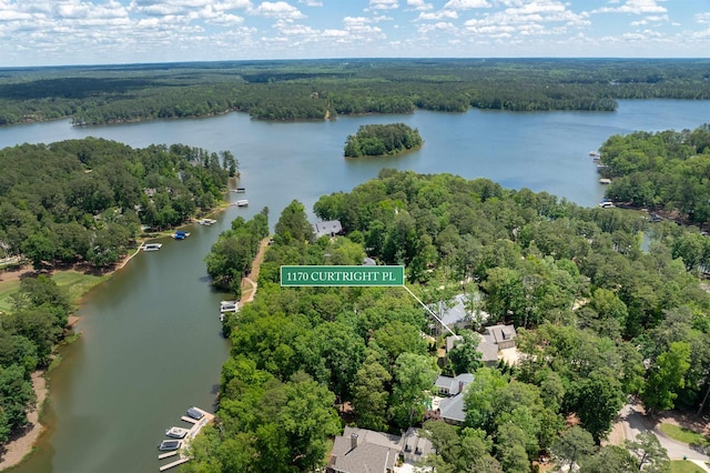 drone / aerial view of a nearby body of water and a heavily wooded area