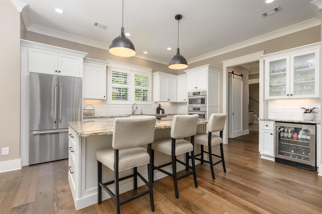 kitchen with high end fridge, wine cooler, a barn door, white cabinetry, and backsplash