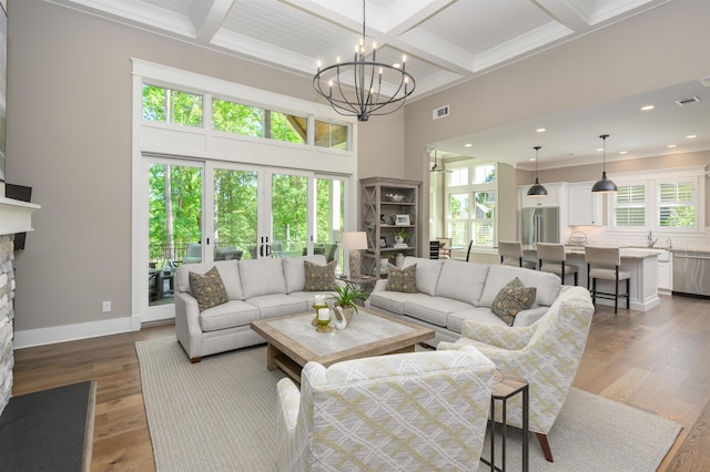 living room with coffered ceiling, a fireplace, beam ceiling, a chandelier, and dark wood finished floors