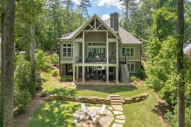 back of house featuring a patio, stairs, a chimney, a yard, and roof with shingles