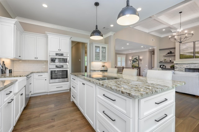 kitchen with appliances with stainless steel finishes, decorative backsplash, beam ceiling, coffered ceiling, and a center island