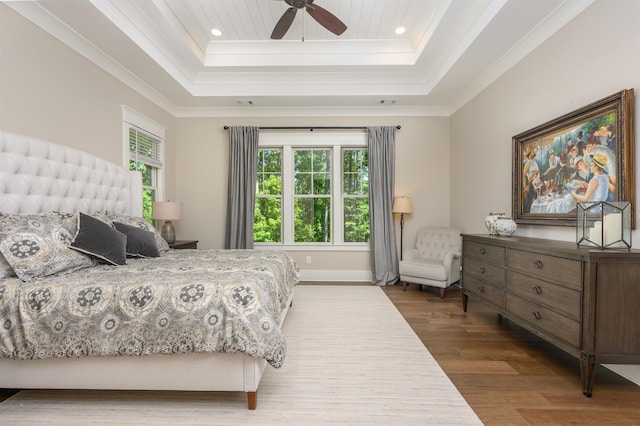 bedroom with a tray ceiling, wood finished floors, recessed lighting, ornamental molding, and a ceiling fan