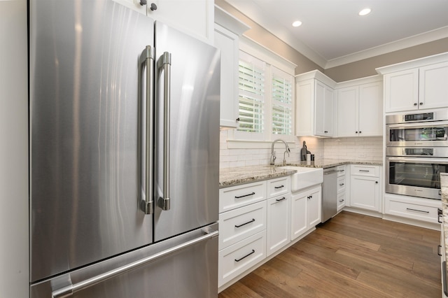 kitchen featuring stainless steel appliances, a sink, white cabinetry, ornamental molding, and recessed lighting