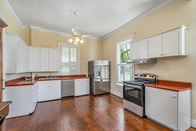 kitchen with stainless steel appliances, ornamental molding, dark hardwood / wood-style floors, and white cabinets