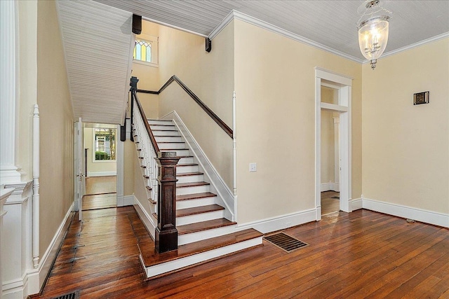 stairs with an inviting chandelier, wood-type flooring, and ornamental molding