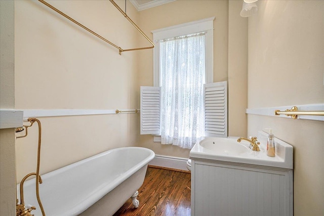 bathroom featuring hardwood / wood-style flooring, a bathing tub, vanity, ornamental molding, and toilet