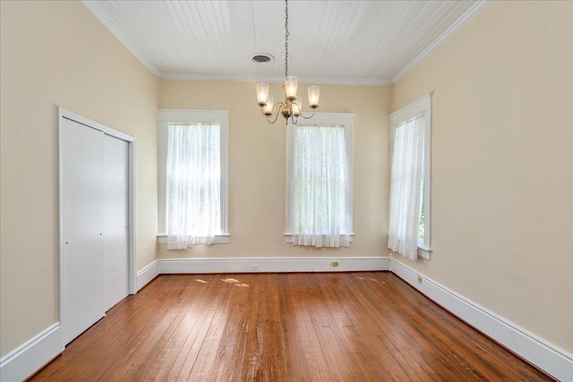 unfurnished dining area featuring an inviting chandelier, ornamental molding, and hardwood / wood-style floors