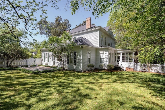 rear view of property with a lawn, a sunroom, and a patio