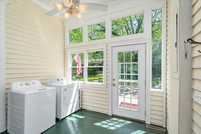 laundry room featuring wooden walls, washing machine and dryer, and ceiling fan