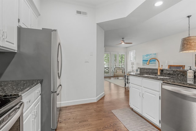 kitchen featuring stainless steel appliances, white cabinetry, hanging light fixtures, and sink