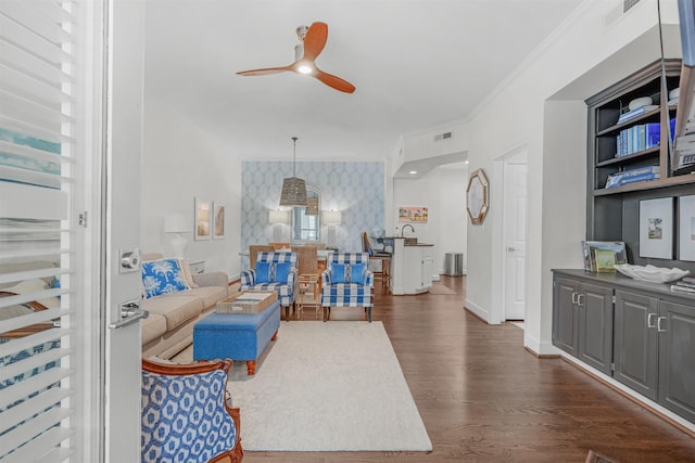 living room with crown molding, ceiling fan, dark hardwood / wood-style floors, and built in features