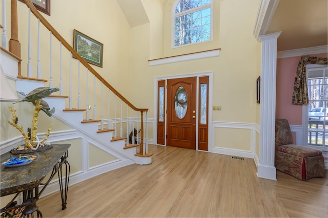 entryway featuring ornamental molding, light hardwood / wood-style floors, and decorative columns