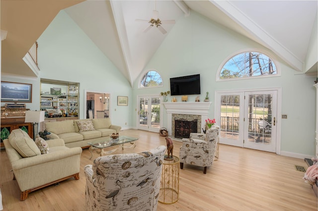 living room featuring a healthy amount of sunlight, a premium fireplace, high vaulted ceiling, and light hardwood / wood-style flooring