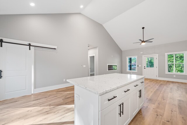 103 Spruce Ln, Eatonton, GA 31024 - kitchen featuring light wood finished floors, a barn door, ceiling fan, a kitchen island, and light stone counters