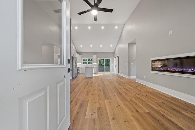 103 Spruce Ln, Eatonton, GA 31024 - unfurnished living room with a glass covered fireplace, ceiling fan, high vaulted ceiling, light wood-style floors, and baseboards