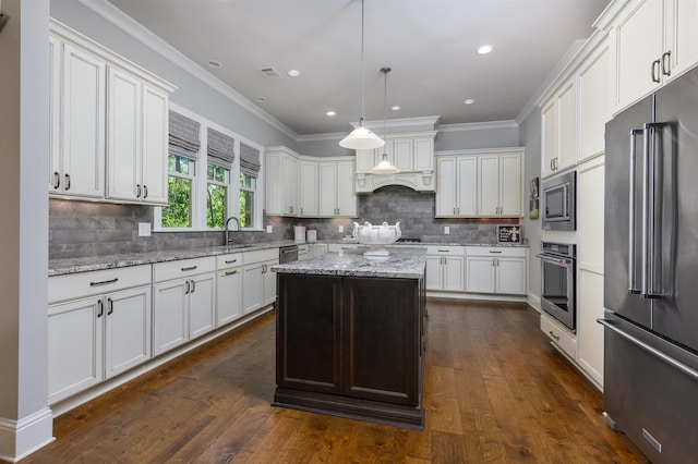 kitchen featuring a kitchen island, white cabinetry, hanging light fixtures, light stone counters, and stainless steel appliances