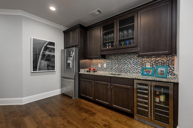 kitchen featuring tasteful backsplash, stainless steel fridge, beverage cooler, dark brown cabinetry, and light stone countertops