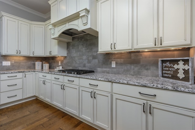 kitchen with white cabinetry, ornamental molding, dark hardwood / wood-style flooring, stainless steel gas stovetop, and decorative backsplash