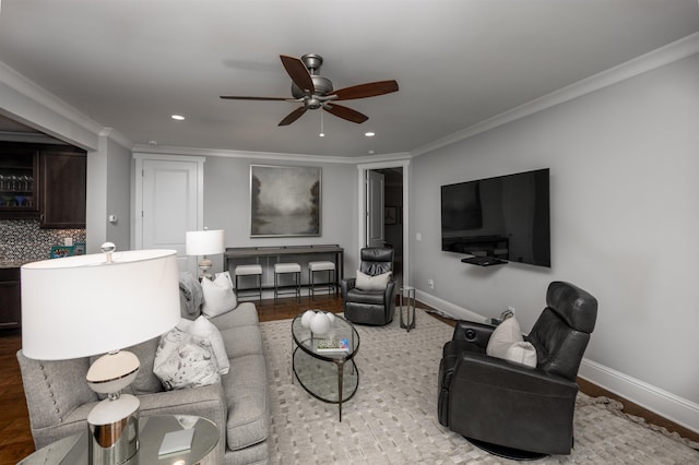 living room with ornamental molding, wood-type flooring, and ceiling fan