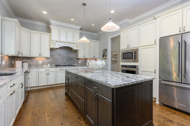 kitchen with pendant lighting, crown molding, stainless steel appliances, tasteful backsplash, and a kitchen island