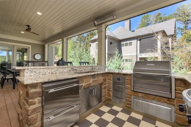 view of patio with ceiling fan, an outdoor kitchen, area for grilling, and an outdoor wet bar