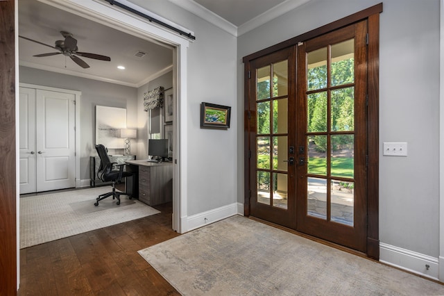 doorway with french doors, dark hardwood / wood-style floors, crown molding, and a barn door