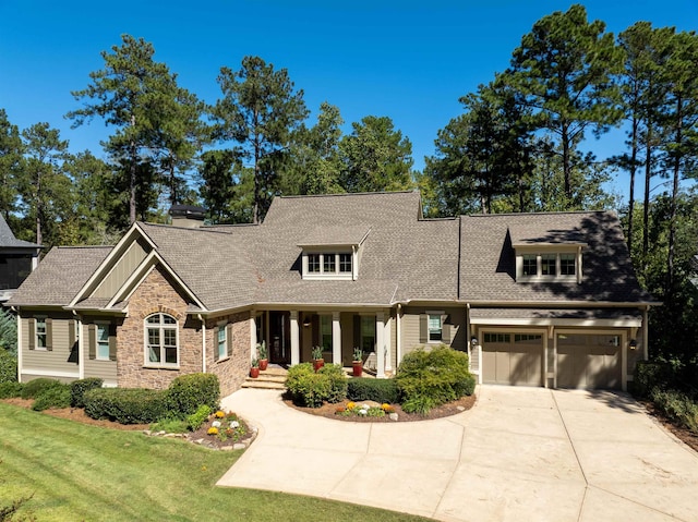 view of front of property featuring a garage, a front lawn, and covered porch