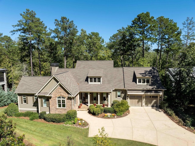 view of front of house featuring a garage, covered porch, and a front lawn