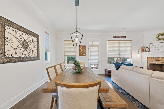 dining area featuring crown molding, a fireplace, and wood-type flooring