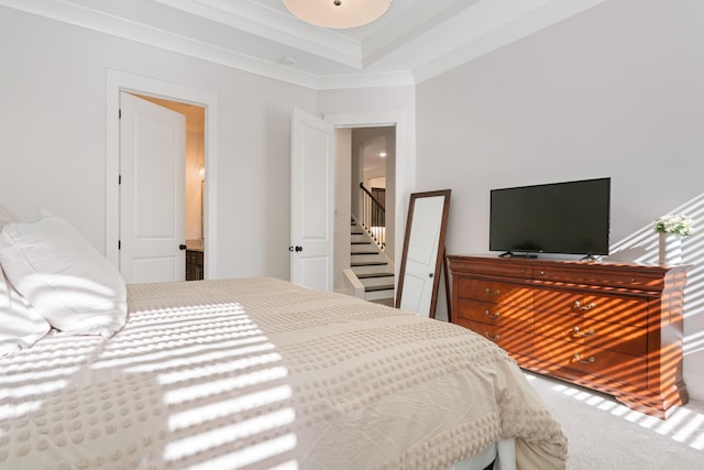 bedroom featuring a raised ceiling, crown molding, and carpet floors