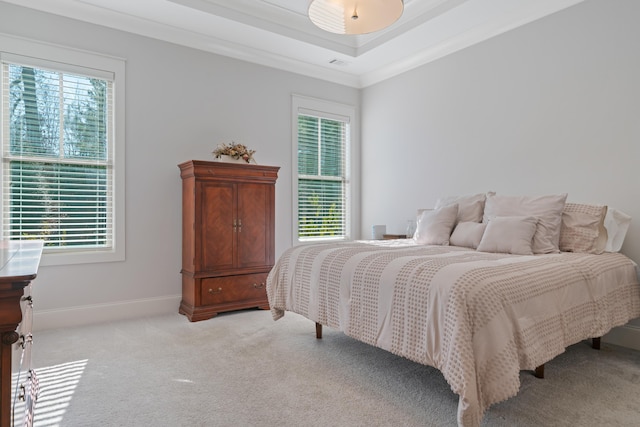 bedroom featuring light carpet, crown molding, multiple windows, and a tray ceiling