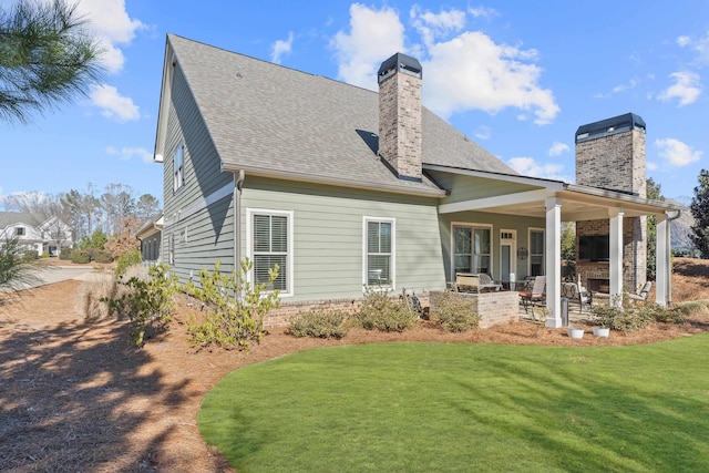 rear view of property with a yard, a fireplace, and a patio area