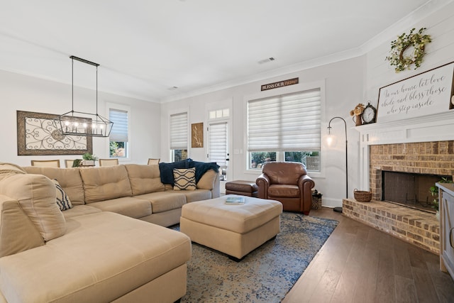 living room featuring crown molding, an inviting chandelier, a fireplace, and dark wood-type flooring