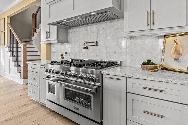 1201 Askew Trl, Greensboro, GA 30642 - kitchen with light stone countertops, light wood-style floors, decorative backsplash, double oven range, and custom exhaust hood