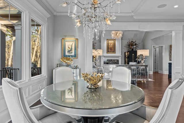 dining room with ornate columns, dark hardwood / wood-style floors, a fireplace, a chandelier, and ornamental molding