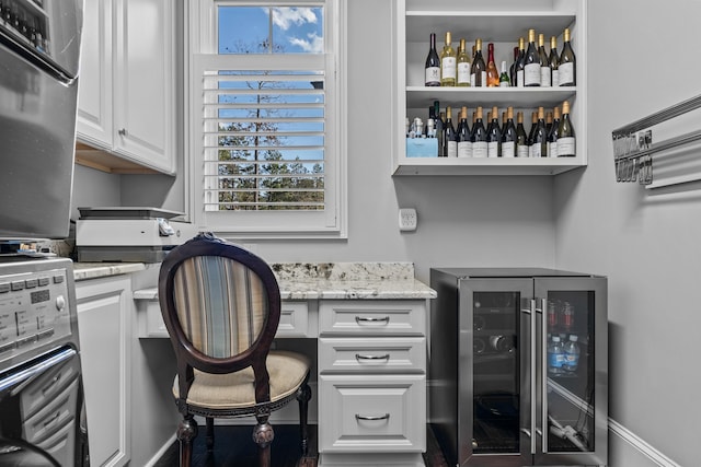 office with wine cooler, indoor bar, a healthy amount of sunlight, and built in desk